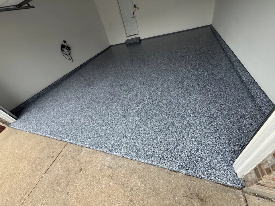 Grey flake epoxy floor coating in a basement, meeting a bare concrete landing at the foot of the stairs