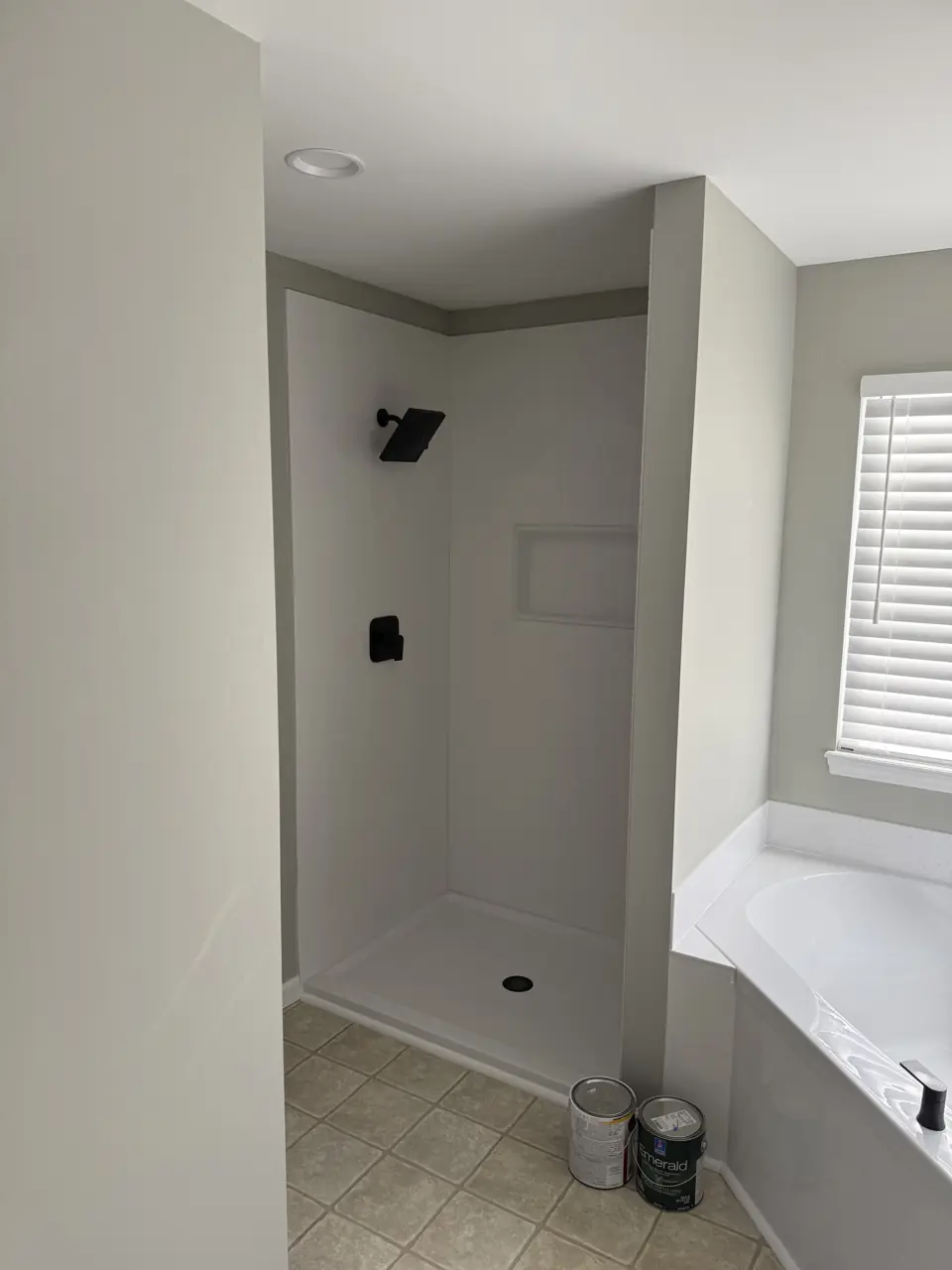 Separate shower with a low curb and matte black fixtures beside a corner tub