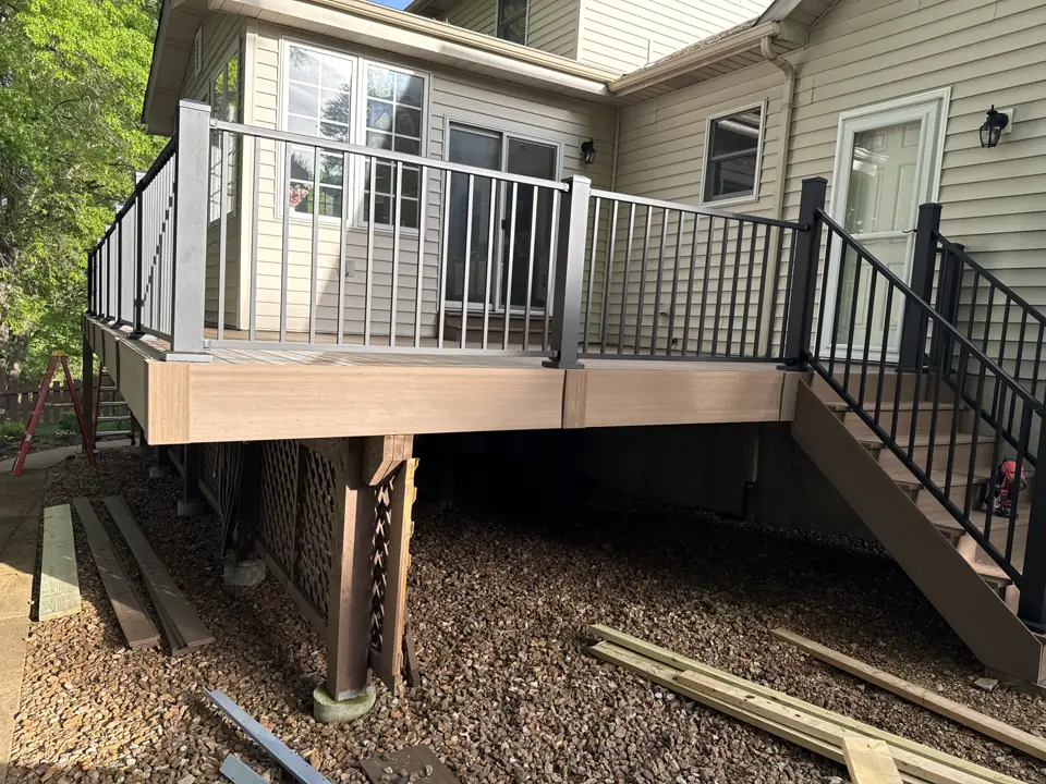 Composite deck with a stair down to a gravel bed, black aluminum railing and new posts