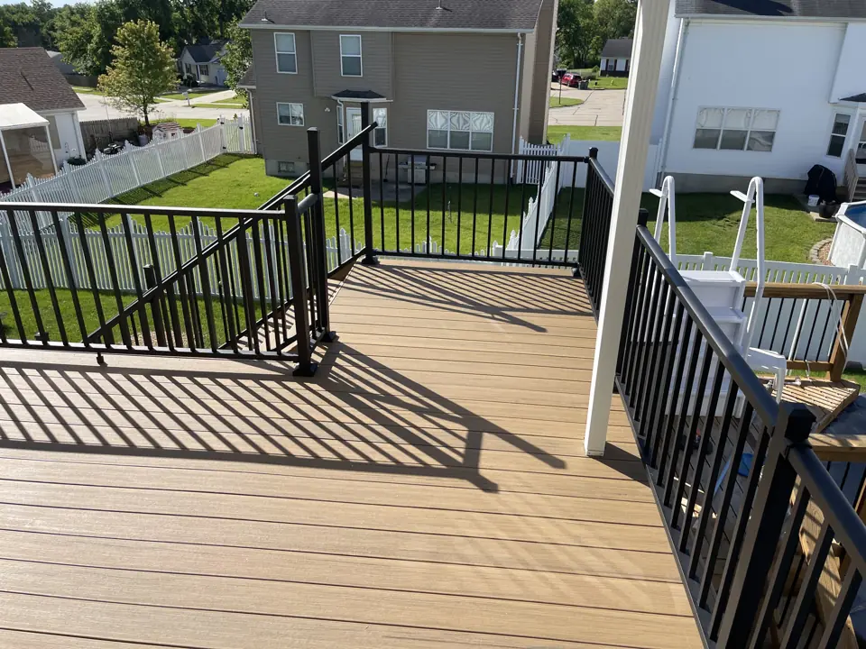 Open section of a brown composite deck with a picture-frame border and black aluminum picket railing