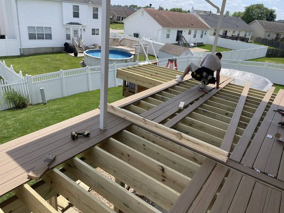 Carpenter fastening composite deck boards over pressure-treated joists on a second-story deck