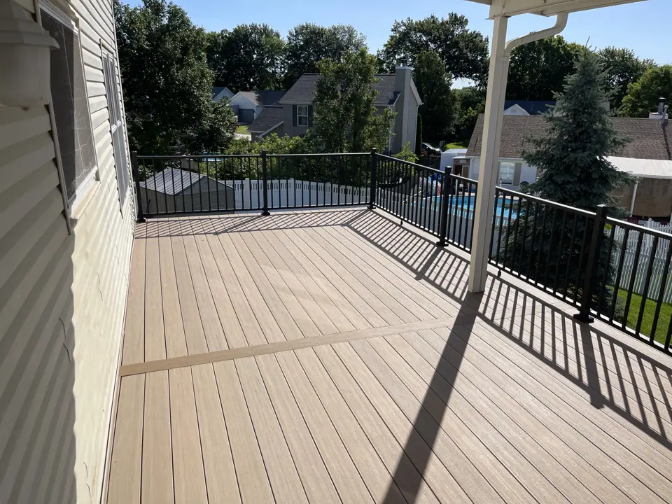 Brown composite deck with black aluminum railing looking out over the neighborhood, aluminum roof post at the corner