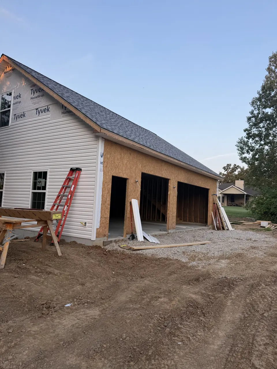 Three-bay detached garage with a new shingle roof and white siding, seen from the drive