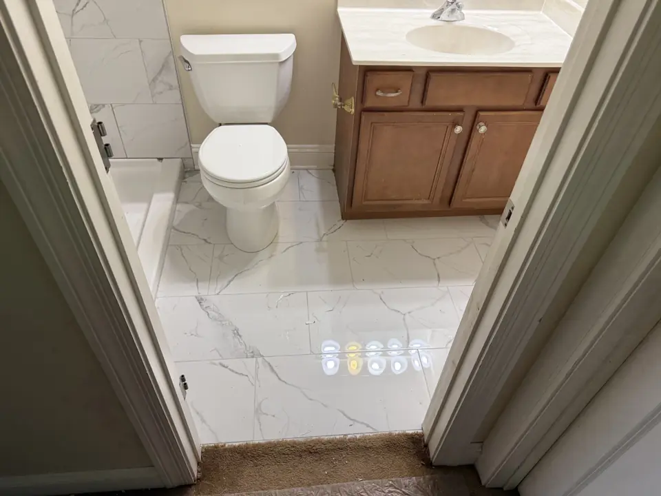 Hall bathroom with glossy porcelain floor tile, white toilet and an oak vanity with white top