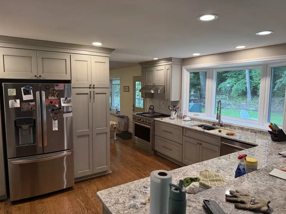 Grey kitchen with a pantry cabinet beside the refrigerator and a wide window over the sink