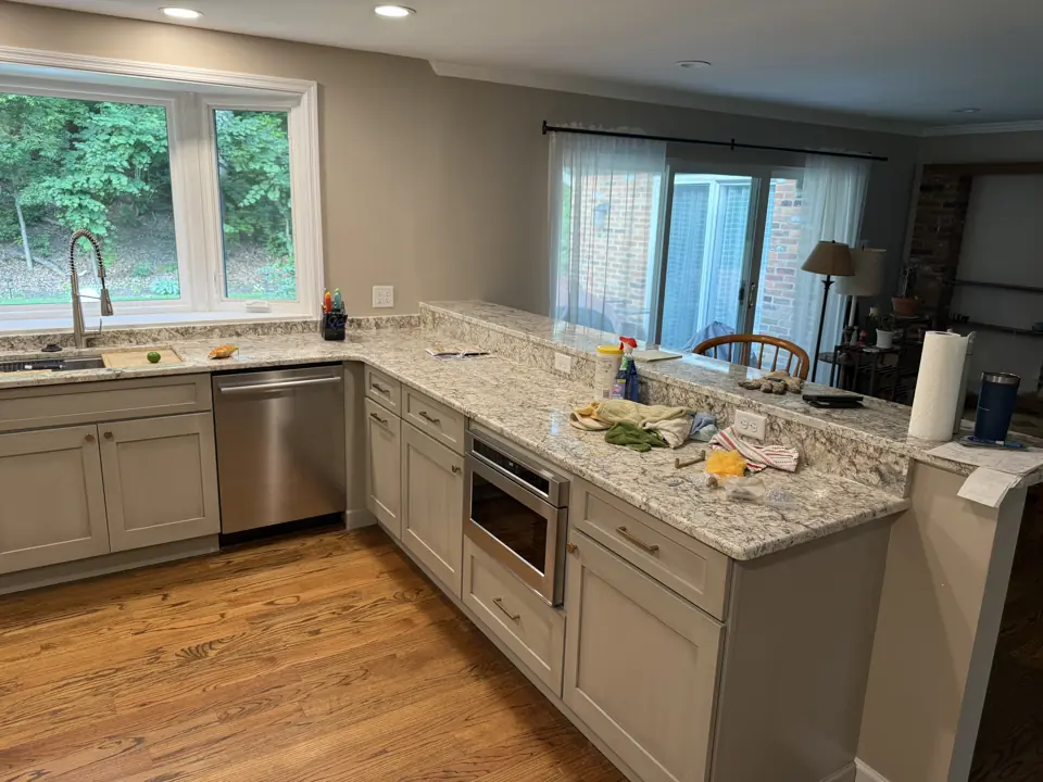 Kitchen peninsula with granite counter, dishwasher and undercounter microwave, hardwood floor continuing into the dining area