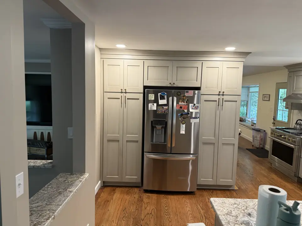 Full-height grey pantry cabinets flanking a stainless refrigerator