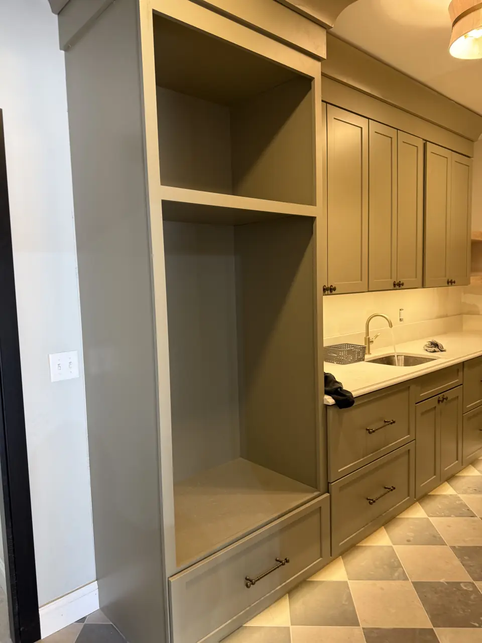 Mudroom with a built-in bench and cubby, sage cabinetry, a small sink and a checkerboard stone floor