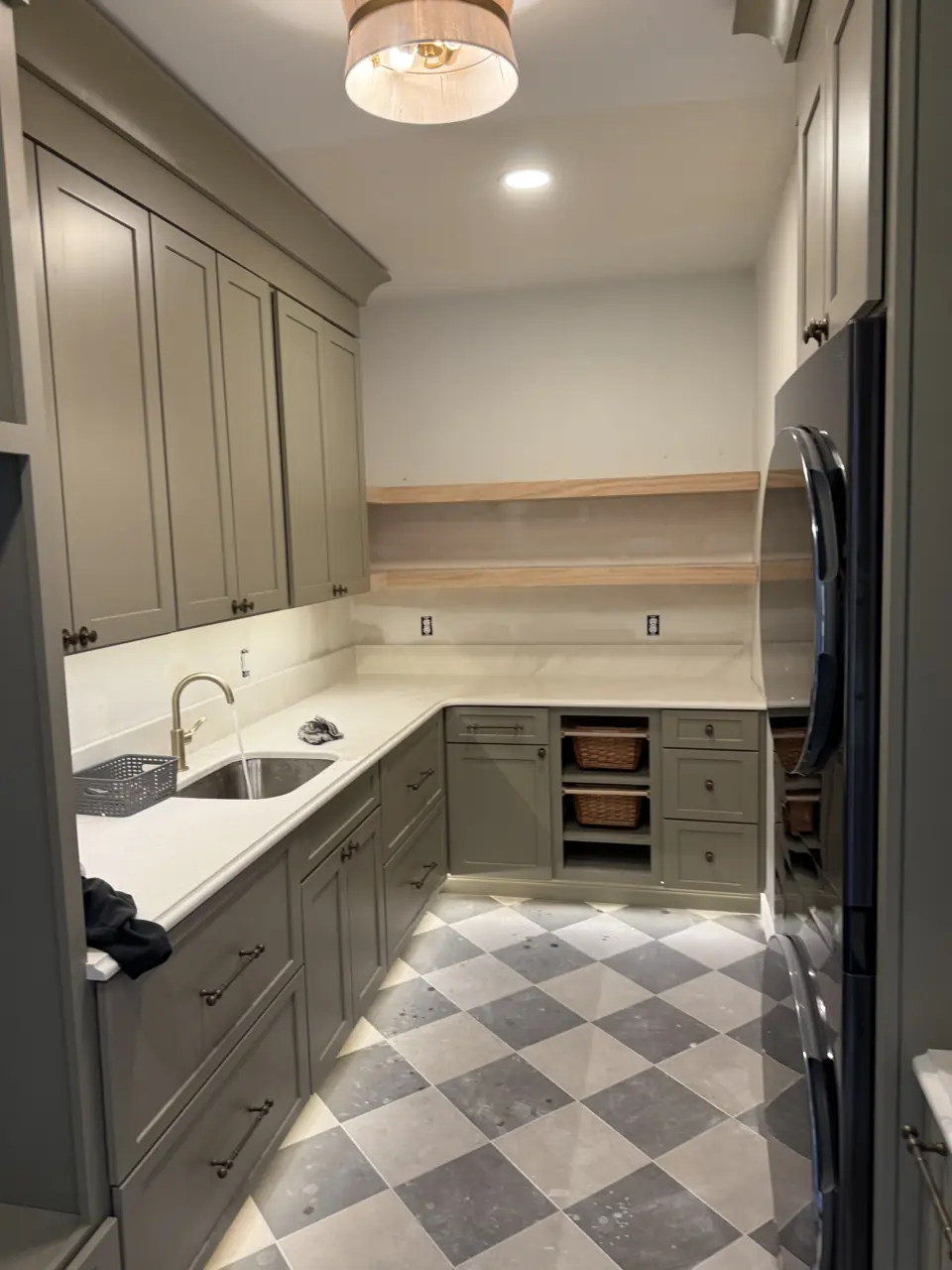 Sage cabinet run with open shelf, sink and refrigerator in the mudroom, checkerboard floor, from the doorway